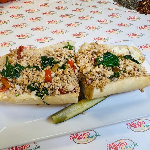 Allegro Pizza's chicken cheesesteak with spinach and red peppers, served with a pickle spear.