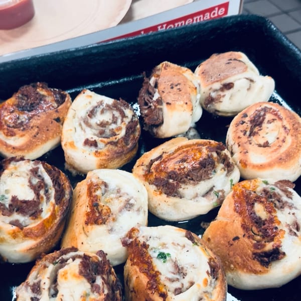 Close-up of baked Allegro Pizza rolls with meat and cheese filling in a black pan.
