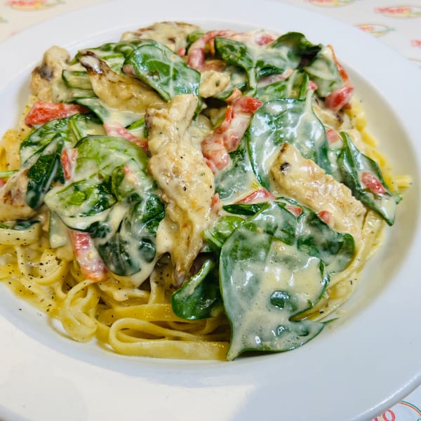 Allegro Pizza's creamy pasta with chicken, spinach, and red peppers on a white plate.