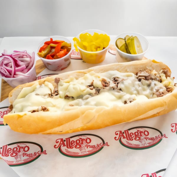 Allegro Pizza's cheesesteak sub with melted cheese, served with sides of pickled onions, peppers, and pickles.
